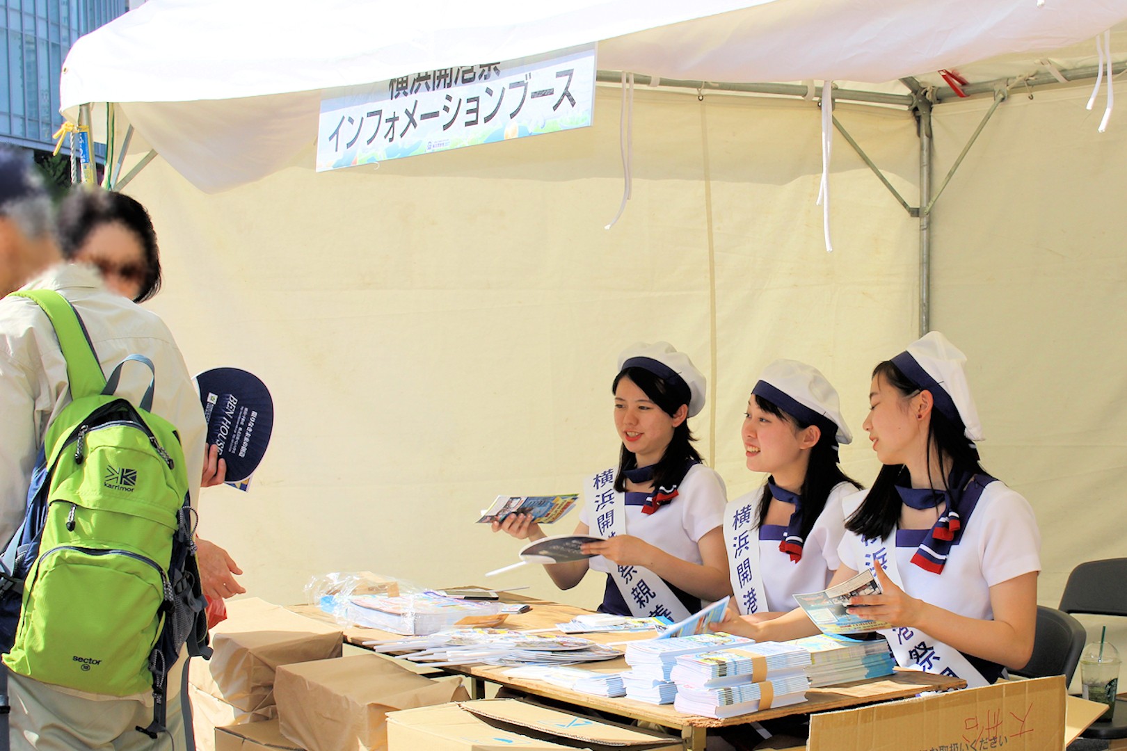 来場者にうちわを配る横浜開港親善大使の上田美結さん、生田和香奈さん、持田凪沙さん（JR桜木町駅前）