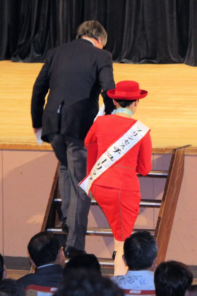 壇上に上がる砺波市の夏野修市長を支えるプリンセスチューリップの島田万由さん